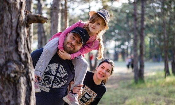 A joyful family enjoying a playful day in a sunlit forest park, capturing the essence of togetherness.